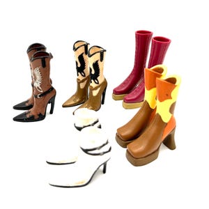May include: A collection of miniature cowboy boots in various colors and designs. The boots include brown, white, red, and tan, with decorative stitching and high heels. Some boots feature a pointed toe, while others have a square toe.