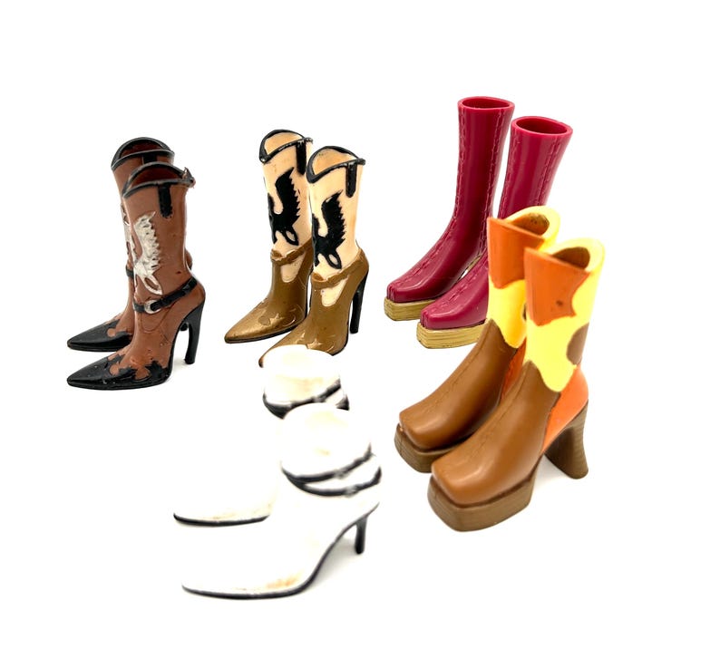 May include: A collection of miniature cowboy boots in various colors and designs. The boots include brown, white, red, and tan, with decorative stitching and high heels. Some boots feature a pointed toe, while others have a square toe.