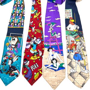 May include: Four patterned neckties with cartoon character designs. One tie features a hockey scene with Taz, another has a golf theme with Goofy, a third shows Bugs Bunny at the beach, and the last one has a billiards theme with Daffy Duck.
