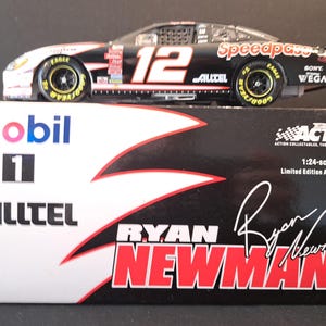 May include: A black, white, and red Ryan Newman #12 race car model, 1:24 scale, with "Speedpass" and "Alltel" logos. The box reads "Mobil 1" and "Ryan Newman". The car has yellow Goodyear Eagle tires.