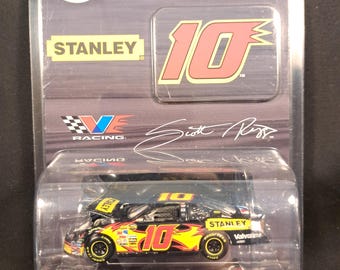 May include: A 1:64-scale NASCAR stock car in a clear plastic case. The car is black, yellow, and red with the number 10 and Stanley branding. The packaging includes the NASCAR logo and text that reads "Limited Edition Adult Collectible."