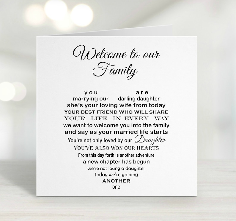 May include: A white wedding card with black script. The card reads "Welcome to our Family" at the top, followed by a poem welcoming a new family member. The word "Daughter" is in a cursive font.