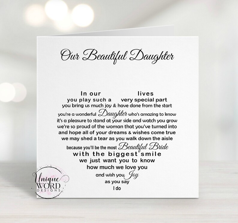May include: A white greeting card with the text "Our Beautiful Daughter" in elegant script. The card contains a heartfelt message about a daughter's wedding, with the words arranged in a heart shape. The card is from Unique Word Designs.