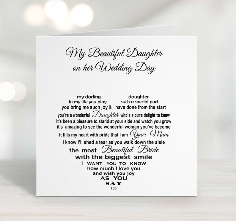May include: A white wedding card with black script. The text reads "My Beautiful Daughter on her Wedding Day." Inside, a heart-shaped arrangement of text includes phrases like "Beautiful Bride" and "I do." The card is a sentimental gift.