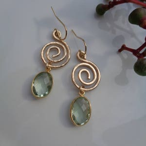 Puede incluir: Pendientes de oro con un diseño en espiral y una piedra ovalada verde claro.