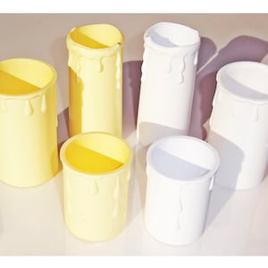 May include: Six white and yellow candle holders with a drip design. The candle holders are made of plastic and are ideal for decorating a home or party.