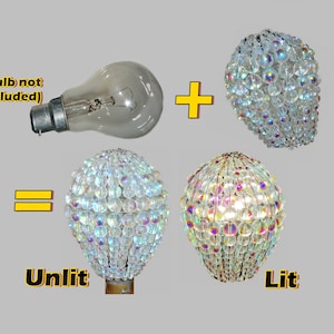 May include: A clear glass light bulb with a standard base is shown next to a crystal chandelier. The chandelier is shown unlit and lit. The text "Bulb not included" is shown above the light bulb. The text "Unlit" is shown below the unlit chandelier. The text "Lit" is shown below the lit chandelier.