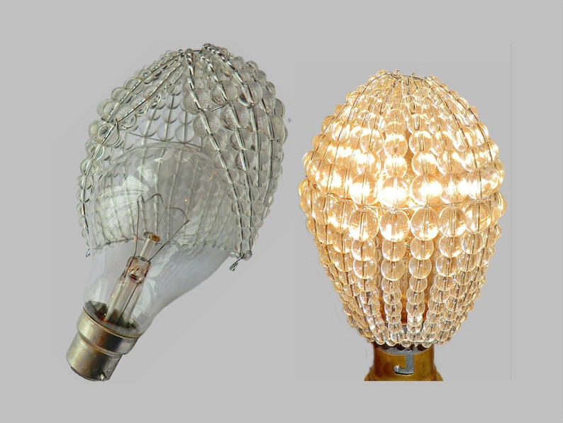 May include: A clear glass light bulb cover with a beaded design. The cover is made of small, round beads that are strung together in a pattern. The cover is shown on a light bulb, both on and off.