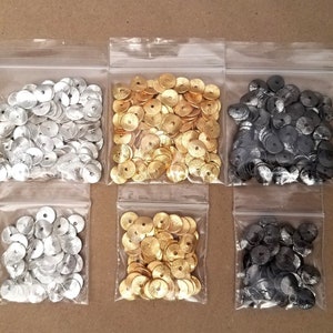 May include: Six small bags of metallic round sequins. The bags are clear plastic and contain silver, gold, and black sequins.