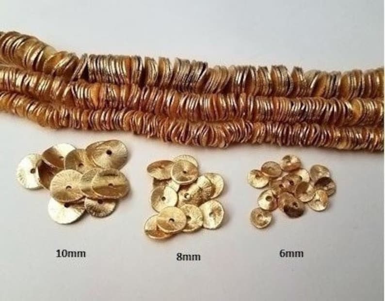 May include: Gold metallic round sequins in three sizes: 10mm, 8mm, and 6mm. The sequins are arranged in piles on a white surface.