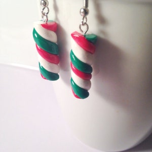 May include: A pair of silver dangle earrings with red, white, and green candy cane-shaped charms.