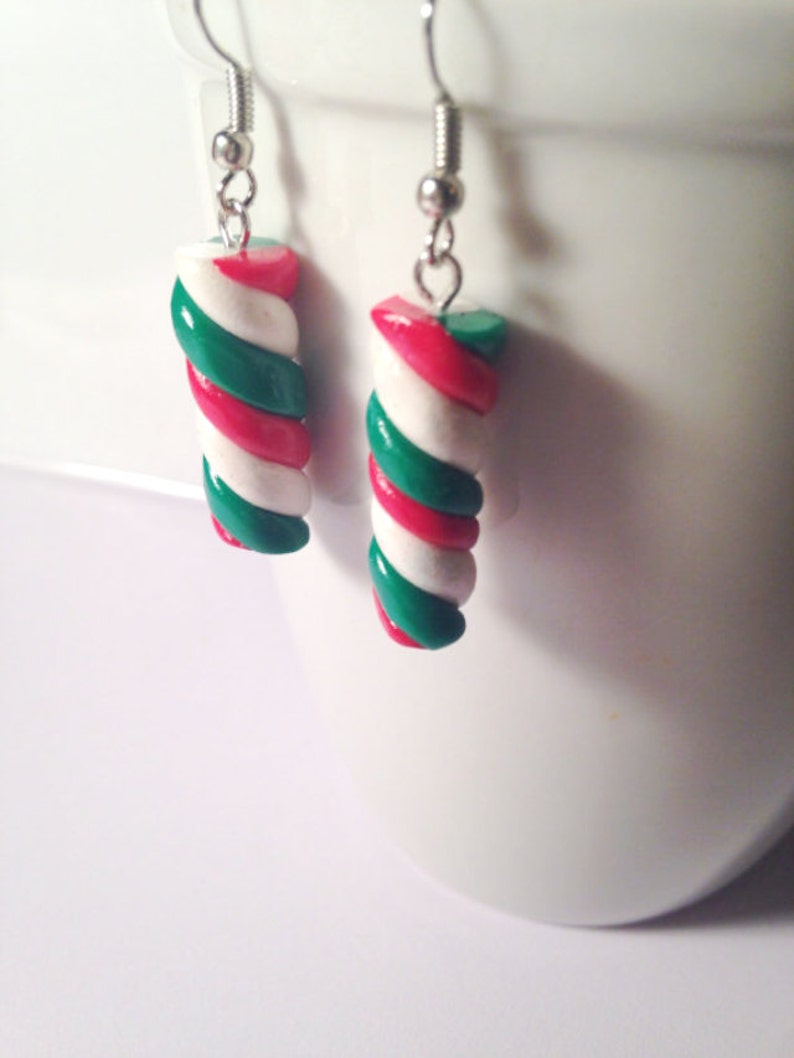 May include: A pair of silver dangle earrings with red, white, and green candy cane-shaped charms.