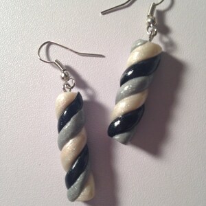 May include: A pair of silver dangle earrings with a white, black, and silver twisted candy cane design.