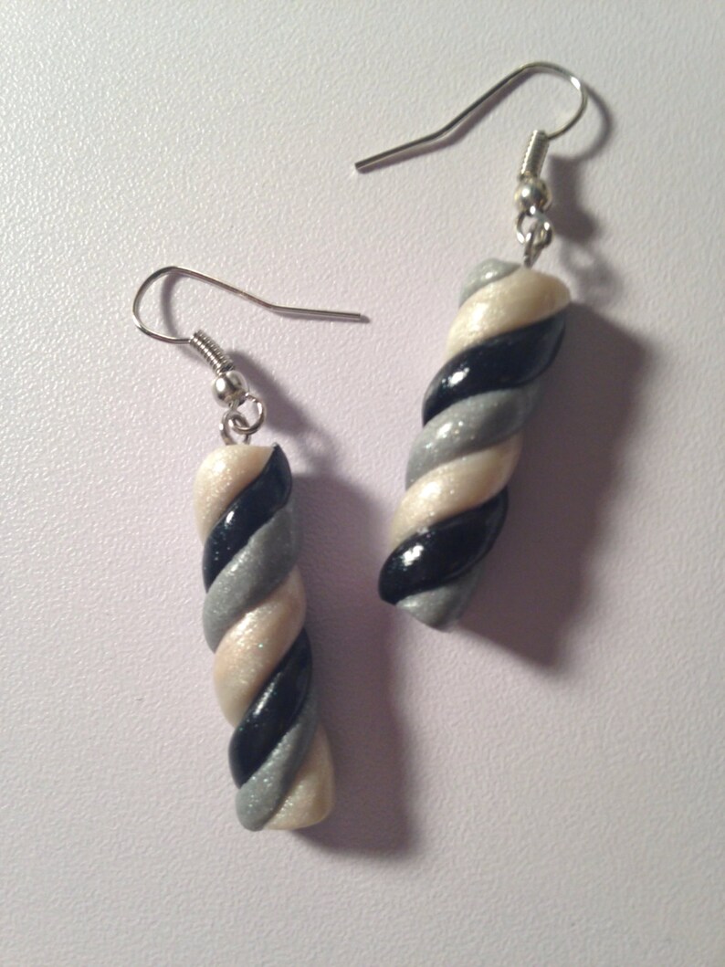May include: A pair of silver dangle earrings with a white, black, and silver twisted candy cane design.