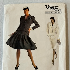 May include: Vogue Patterns sewing pattern featuring designs by Bill Blass. The cover shows illustrations of two women in suits. The pattern is labeled "American Designer" and includes the text "ADVANCED/PLUS DIFFICILE" and "PATTERN/PATRON 2014."