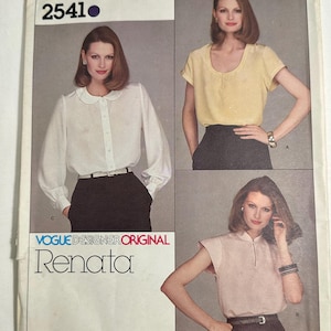 May include: A Vogue Designer Original sewing pattern envelope labeled 2541 Renata. The front displays three blouse variations: a long-sleeved white shirt with a rounded collar, a short-sleeved yellow top with a scoop neck, and a pale pink sleeveless top.
