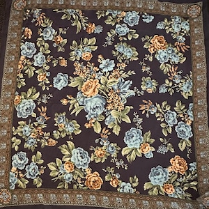 May include: A dark brown square scarf with a floral pattern. The flowers are blue, yellow, and green. The scarf has a brown and gold border.