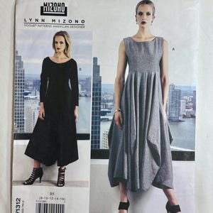 May include: A Vogue Patterns sewing pattern envelope for Lynn Mizono design V1312, featuring a sleeveless grey dress and a long-sleeved black dress. Both garments have a scoop neckline and a full, pleated skirt with an asymmetrical hemline.
