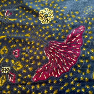 Puede incluir: Una tela azul oscuro con un patrón repetitivo de flores y hojas estilizadas en tonos de amarillo, rojo y blanco.