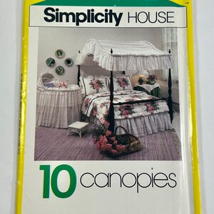 May include: A Simplicity House sewing pattern envelope for 10 canopies. The yellow-bordered package features a photograph of a four-poster bed with a white ruffled canopy, a matching bassinet, and floral bedding. The text reads Simplicity HOUSE.