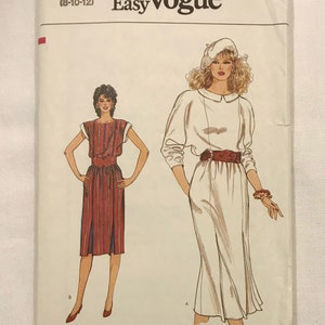 May include: A vintage Very Easy Vogue sewing pattern envelope. The cover features illustrations of two dresses. One is a red and white striped dress, and the other is a white dress with a brown belt. The text "Very Easy Vogue" is at the top.