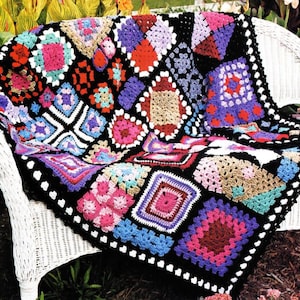 May include: A colorful crocheted throw blanket with a black border and a variety of square patterns in pink, blue, purple, and green.