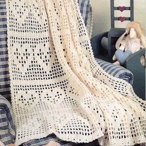 May include: A crocheted throw blanket in a cream colour with a lacy pattern. The blanket is draped over a blue and white checked armchair.