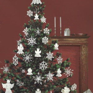 以下が含まれることがあります： 白いクロシェの雪片と天使で飾られたクリスマスツリー。ツリーは赤い壁に立てかけられており、ツリーの上に木の暖炉があります。