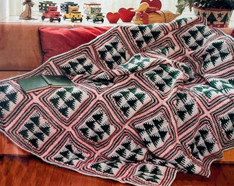 May include: A handmade crochet blanket with a repeating pattern of green Christmas trees on a cream background, framed by red and black borders. The blanket is draped over a sofa, with two books resting on it.