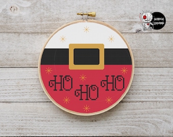 Op de afbeelding: Een rood en wit kruissteek-hoepel met een zwarte riem en een gouden gesp, en de woorden "HO HO HO" in zwart. De achtergrond is een wit houtnerf oppervlak.