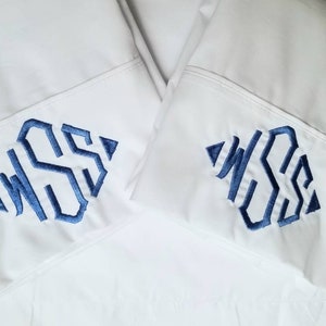 以下が含まれることがあります： 青い刺繍のモノグラムが施された白い枕カバーが2枚。左側の枕カバーのモノグラムは「WSS」、右側の枕カバーのモノグラムは「WS」です。