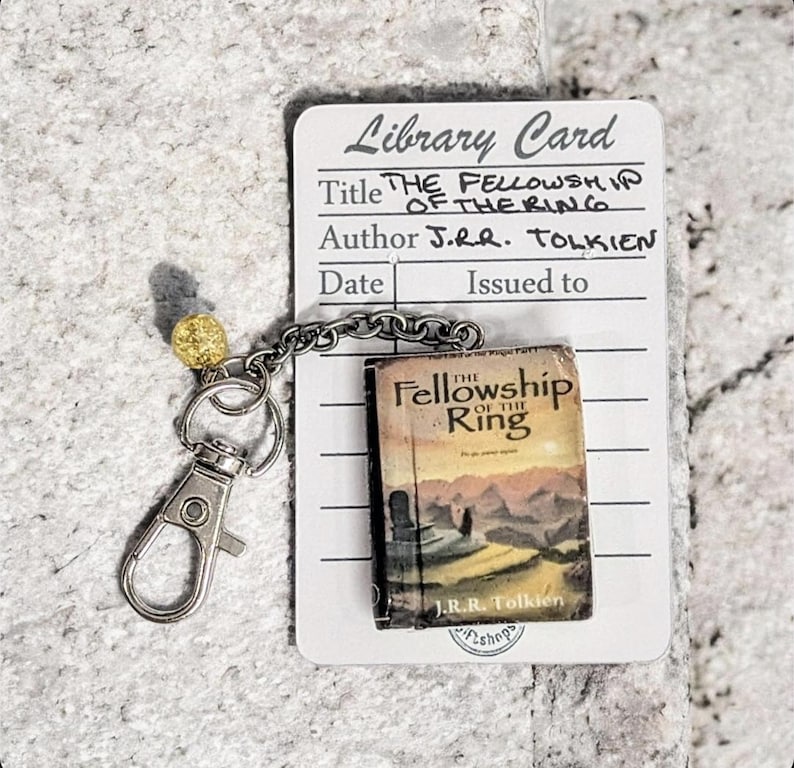 Pu&ograve; includere: Un portachiavi con un libro in miniatura de "La Compagnia dell'Anello" di J.R.R. Tolkien. Il libro &egrave; attaccato a una catena e un fermaglio color argento, con una perla dorata. &Egrave; inclusa anche una scheda della biblioteca con il titolo e l'autore.