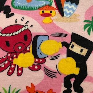 May include: A pink fabric with a cartoon design featuring a red octopus with white polka dots, a black ninja with yellow boxing gloves, a yellow duck with a red umbrella, and a red crab with a black eye.