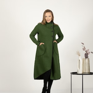 Könnte beinhalten: Ein langer, grüner Mantel mit schwarzem Besatz und einem hohen Kragen. Der Mantel hat einen diagonalen Knopfverschluss und zwei große Taschen.