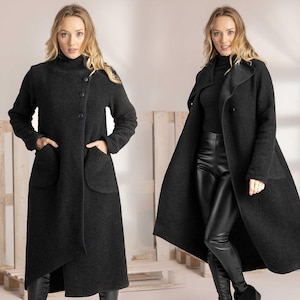 May include: A dark gray wool coat with a high collar and large pockets. The coat has a button closure and a long, flowing design. The model is wearing black pants and boots. The coat is a stylish outerwear option.