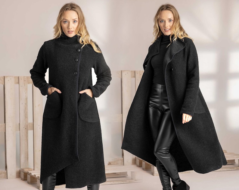 May include: A dark gray wool coat with a high collar and large pockets. The coat has a button closure and a long, flowing design. The model is wearing black pants and boots. The coat is a stylish outerwear option.