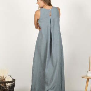 K&ouml;nnte beinhalten: Ein &auml;rmelloses, bodenlanges, hellblaues Kleid mit Schl&uuml;sselloch-R&uuml;cken und Knopfverschluss. Das Kleid hat ein schlichtes, flie&szlig;endes Design, das f&uuml;r l&auml;ssige oder halbformelle Anl&auml;sse geeignet ist. Der Stoff scheint Leinen oder ein &auml;hnliches leichtes Material zu sein.