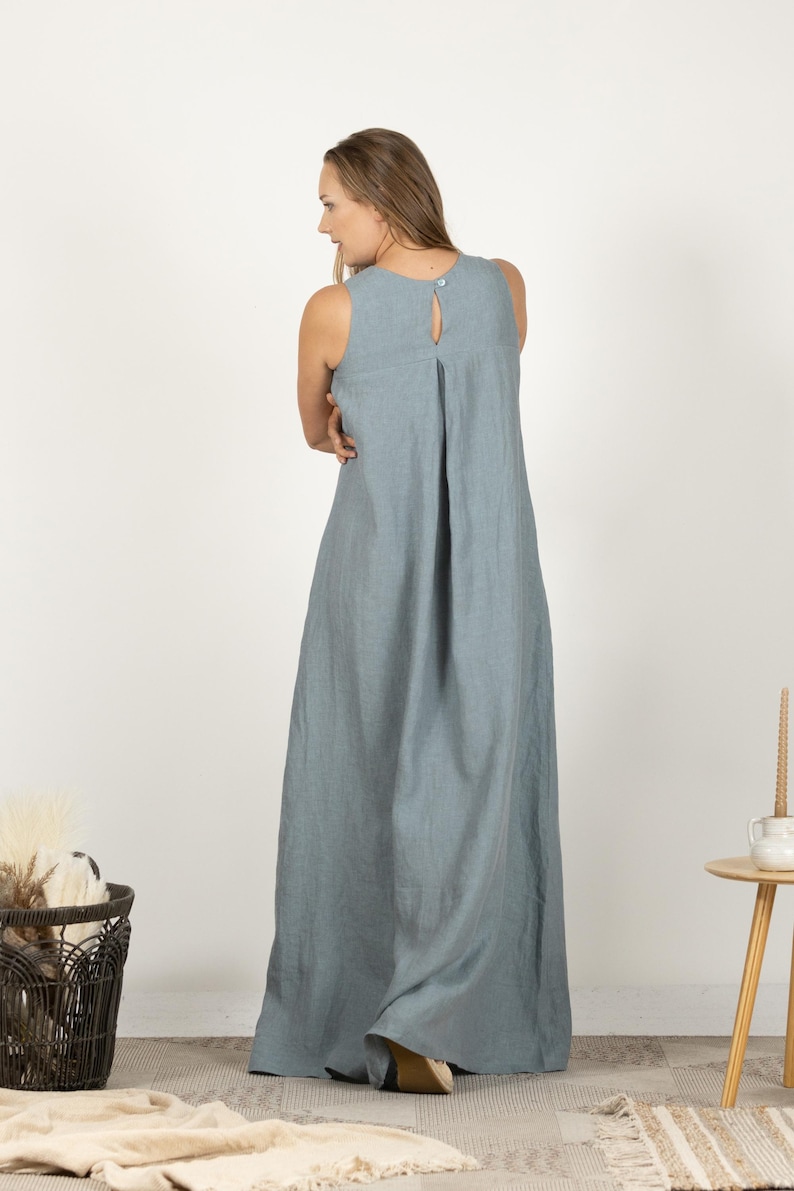 K&ouml;nnte beinhalten: Ein &auml;rmelloses, bodenlanges, hellblaues Kleid mit Schl&uuml;sselloch-R&uuml;cken und Knopfverschluss. Das Kleid hat ein schlichtes, flie&szlig;endes Design, das f&uuml;r l&auml;ssige oder halbformelle Anl&auml;sse geeignet ist. Der Stoff scheint Leinen oder ein &auml;hnliches leichtes Material zu sein.
