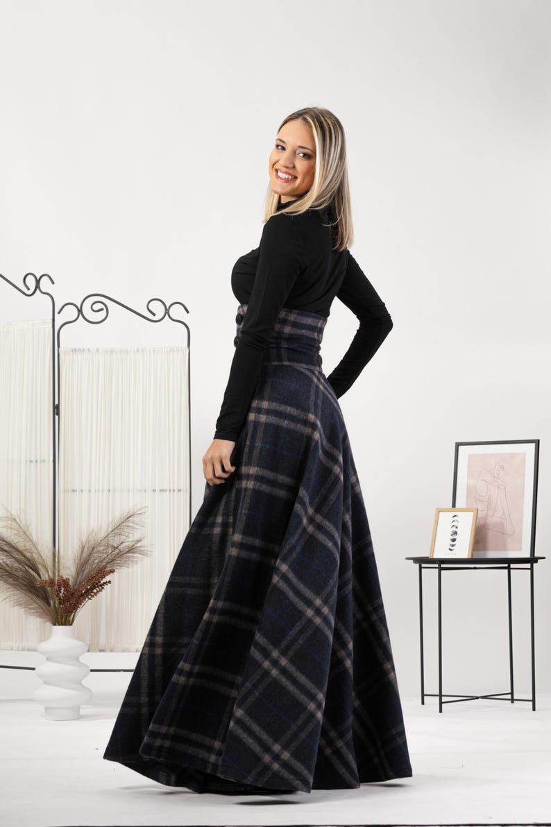 May include: A black long-sleeved top and a high-waisted, navy blue plaid skirt. The skirt has a classic plaid pattern in navy, grey, and brown. The outfit is suitable for various occasions.