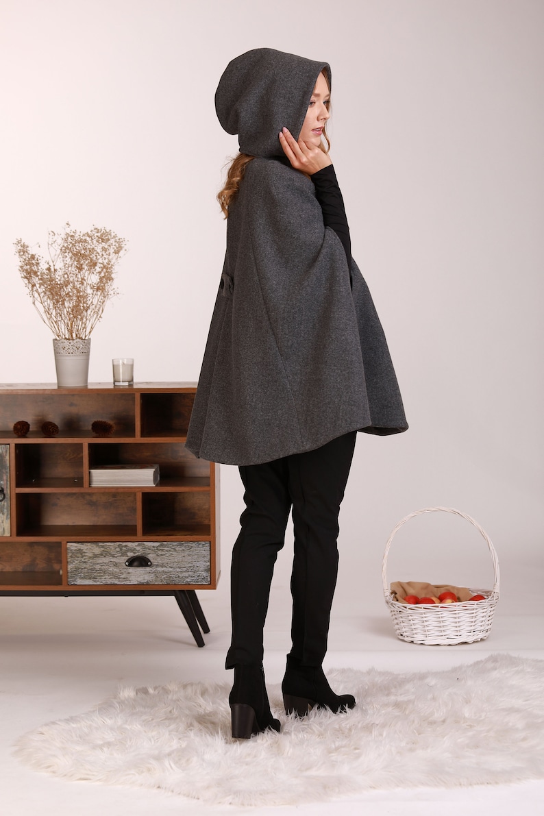 May include: A gray hooded cape with a long, flowing design. The cape is made of a soft, warm fabric and is perfect for keeping you cozy on chilly days.