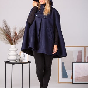 May include: A navy blue hooded cape with a double-breasted button closure. The cape is made of a soft, warm fabric and has a relaxed fit.