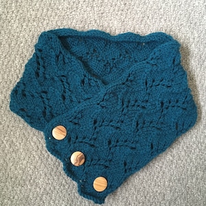 May include: Teal blue crocheted neck warmer with a scalloped edge and three wooden buttons.