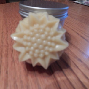 May include: A close-up of a white, star-shaped soap with a textured surface. The soap is shaped like a flower with a raised center.