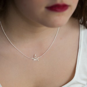 May include: A silver necklace with a delicate origami crane pendant.