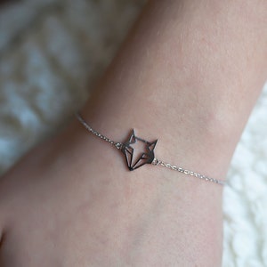 May include: A silver bracelet with a geometric fox pendant.