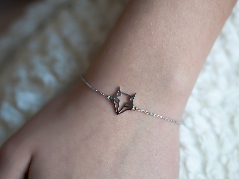 May include: A silver bracelet with a geometric fox pendant.