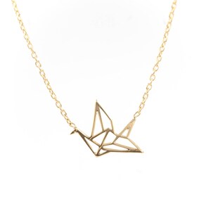 May include: A gold chain necklace with a delicate origami crane pendant.