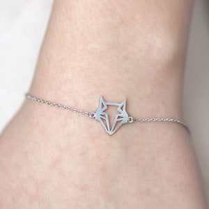 May include: A silver chain bracelet with a geometric fox pendant.
