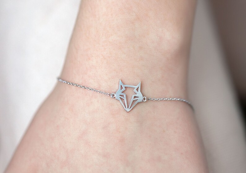 May include: A silver chain bracelet with a geometric fox pendant.