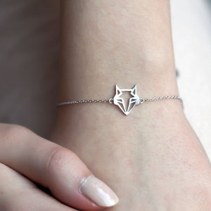 May include: A silver chain bracelet with a geometric fox pendant.